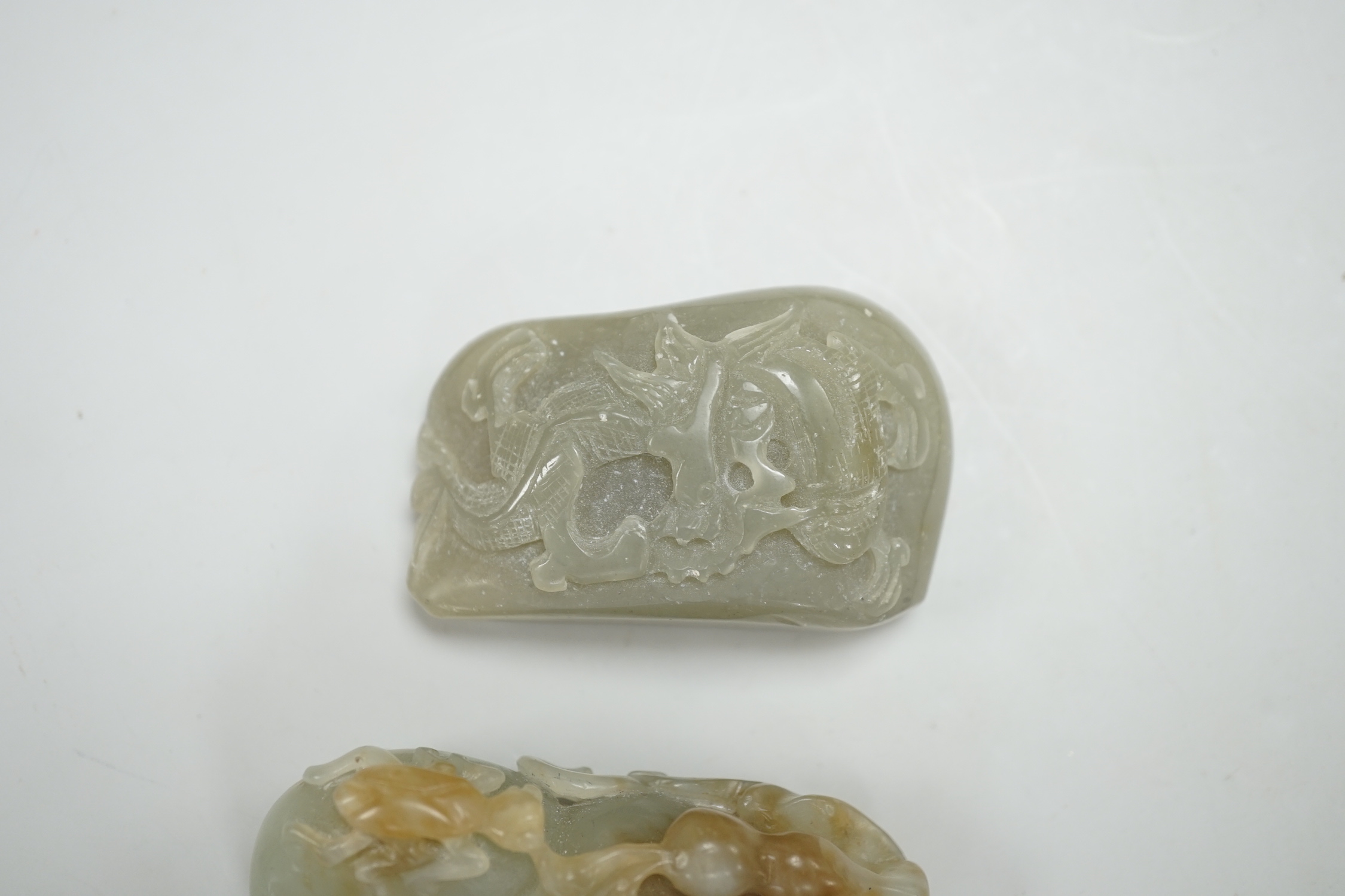 A Chinese green and russet green and brown jade carving of gourd and a green jade pebble carved in relief with a dragon, largest 6.5cm high (2)